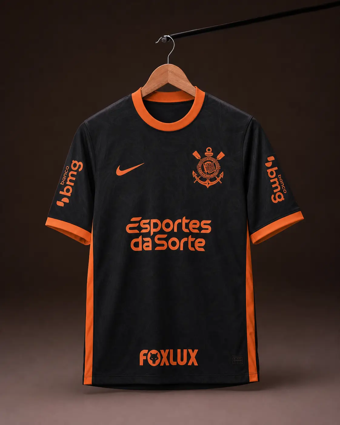 Camisa Corinthians 25/26, preta e laranja, vista de frente em cabide sobre fundo de estudio escuro