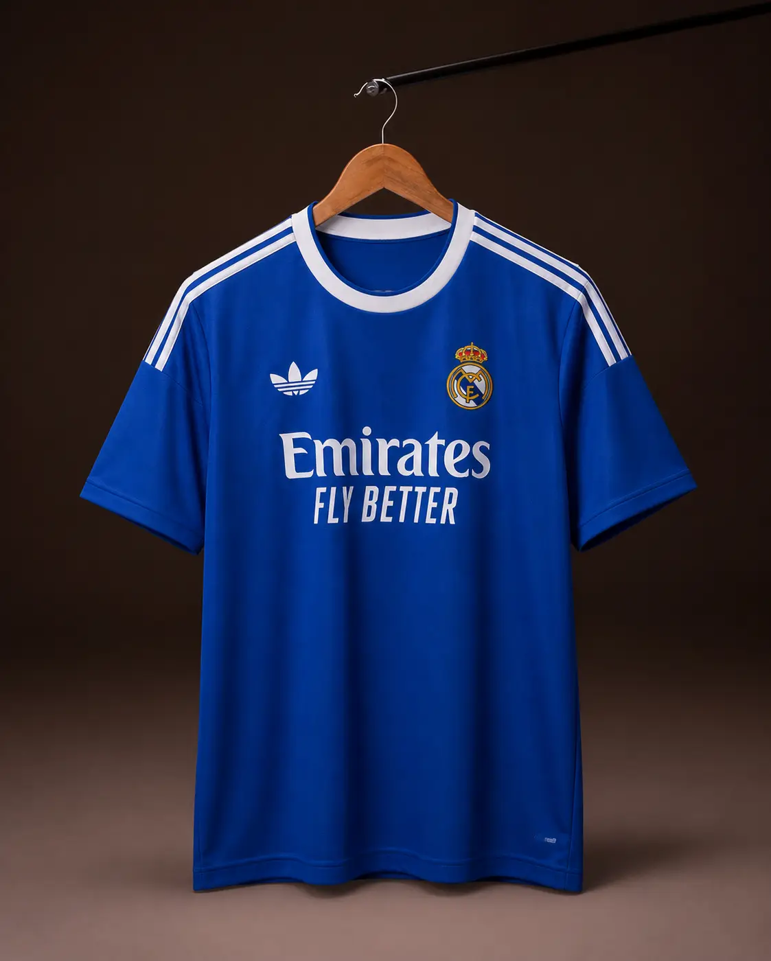 Camisa Real Madrid 25/26, azul, vista de frente em cabide sobre fundo de estudio escuro