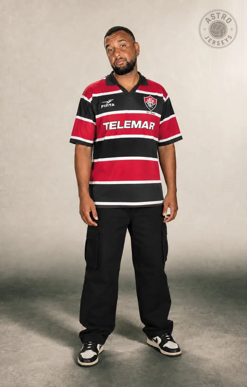 Pessoa de corpo inteiro vestindo a camisa Santa Cruz 1999, tricolor, em estúdio de fundo neutro